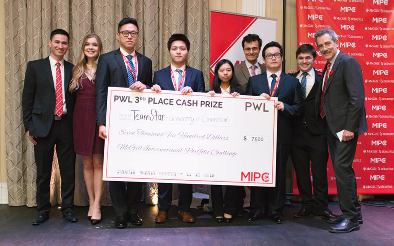 UConn students, from left, Junchao Liao, Xiofan Hou, Xiao Wang and Tuershunjiang Ahemaitijiang hold their check after being recognized as the top U.S. team at the McGill International Portfolio Challenge in Montreal earlier this month. They are surrounded by event organizers. (Photo Courtesy of Jose Aponte)