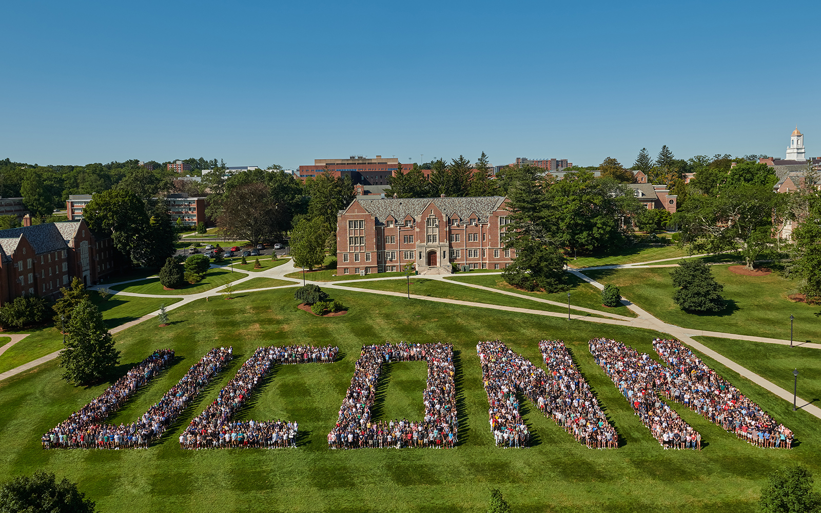 UConn students pose on a lawn, spelling out the word UConn in large block letters. 