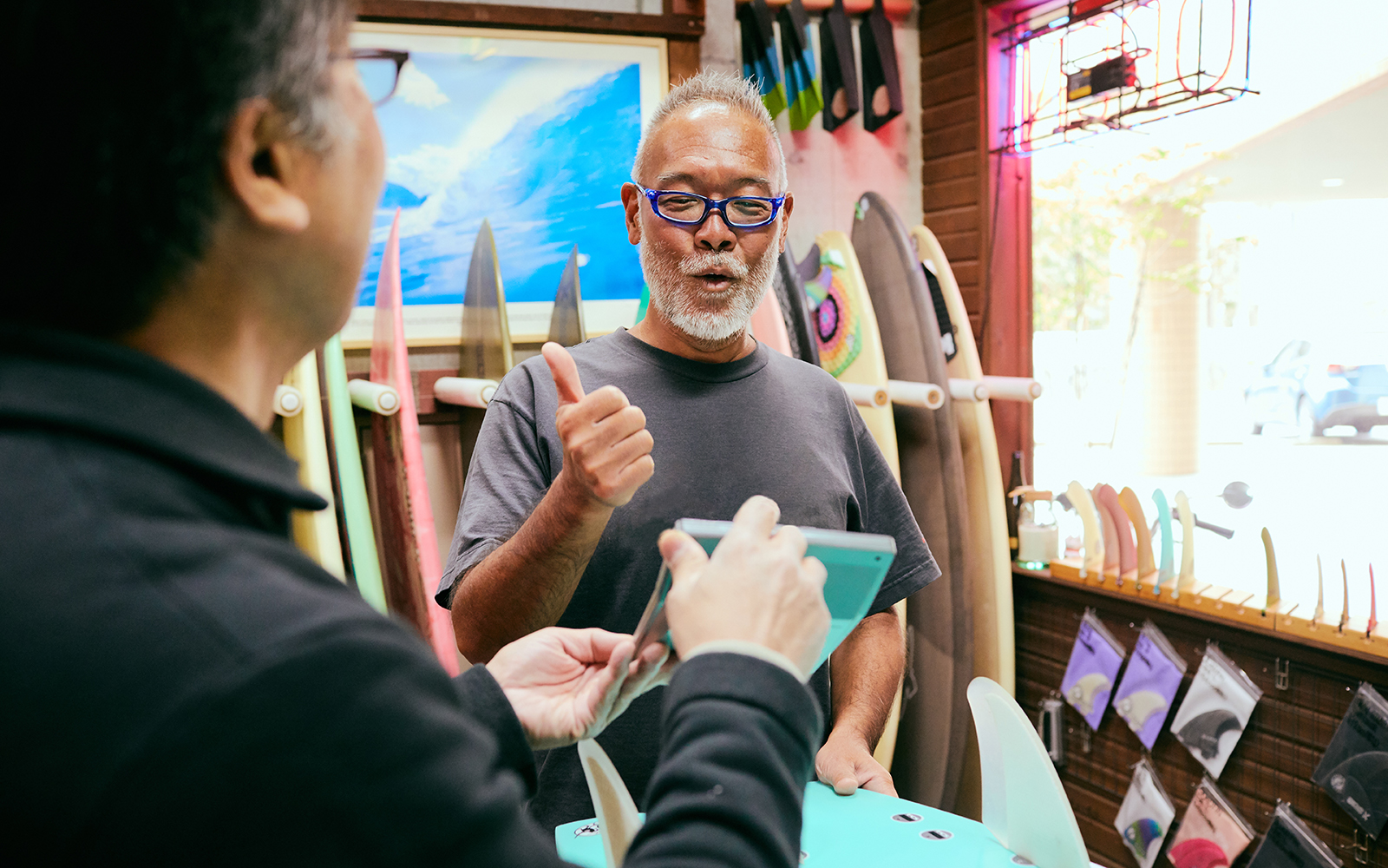 Shopkeeper who presents the amount of surfboards to customers in shop