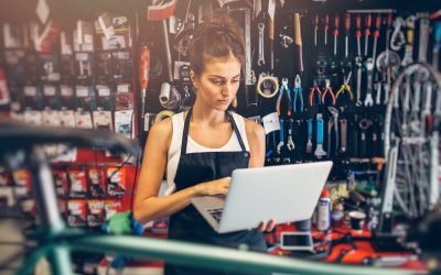 Portrait of a young female bicycle mechanic using a laptop.