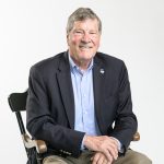 Dean John Elliott seated on a gray background.