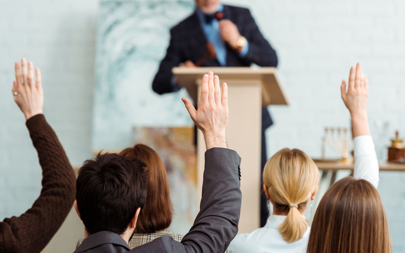 back view of buyers raising hands to auctioneer during auction