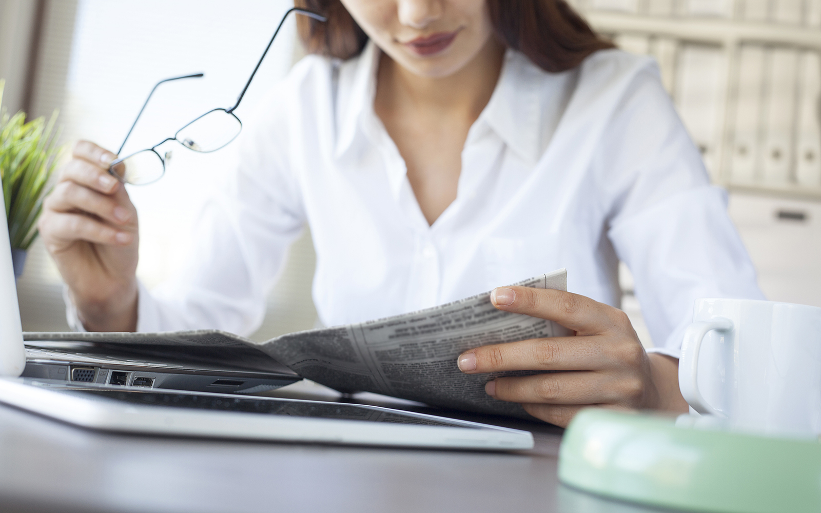 Businesswoman reading newspaper on worktable