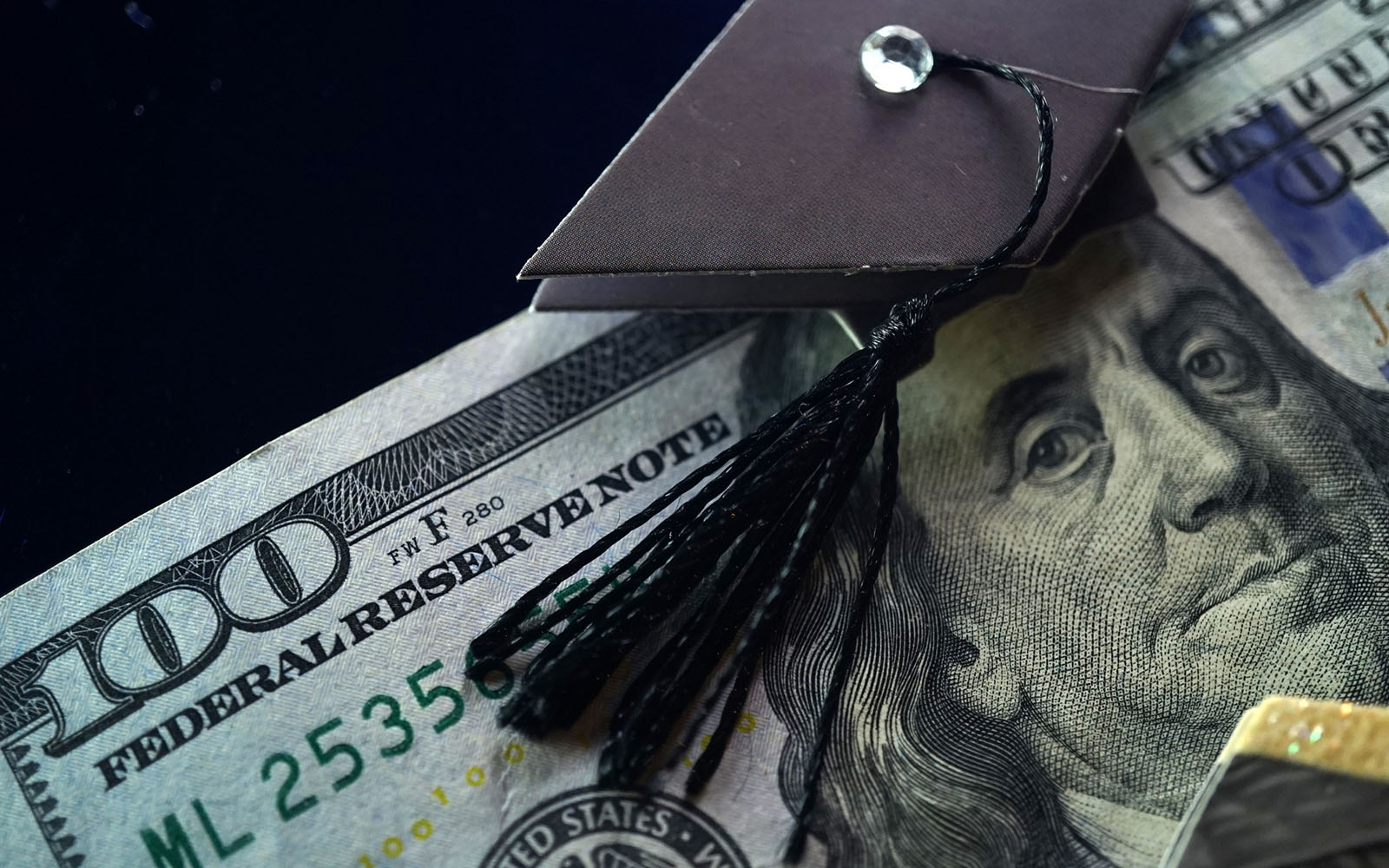 Image of a 100 dollar bill with a academic mortarboard positioned on Ben Franklin's head.