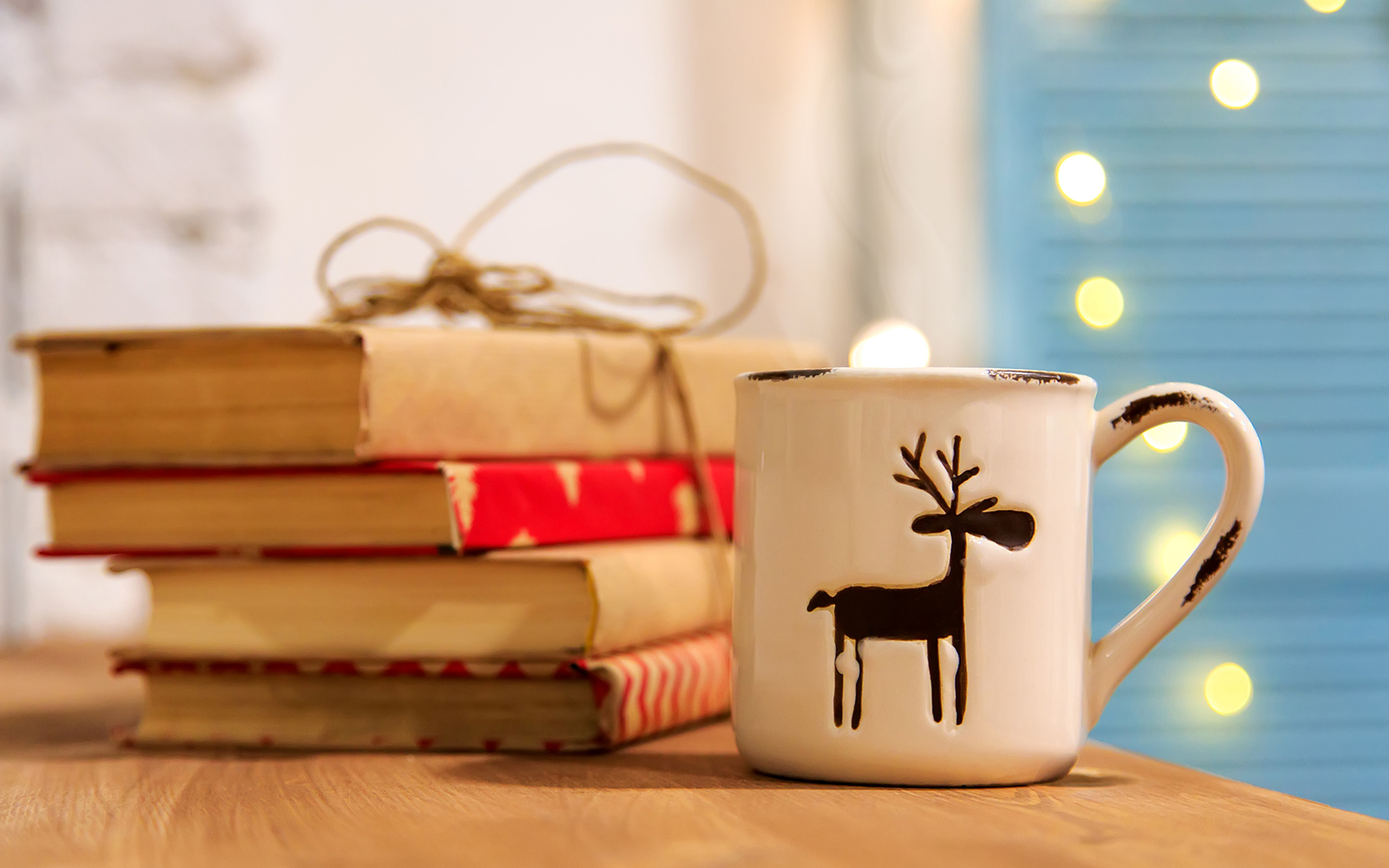 Winter tea. Winter books. A cup of hot tea, books, Christmas shining garland on a wooden background. Winter holidays.