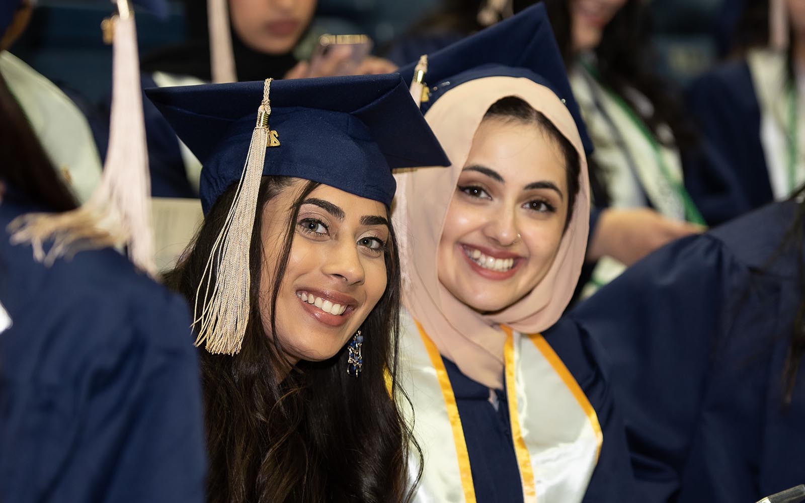 Areesha Khan '22, left and Sahar Sajjad '22, right, both MIS majors, attend the School of Business 2022 Commencement Ceremony at Gampel Pavilion. (Nathan Oldham / UConn School of Business)